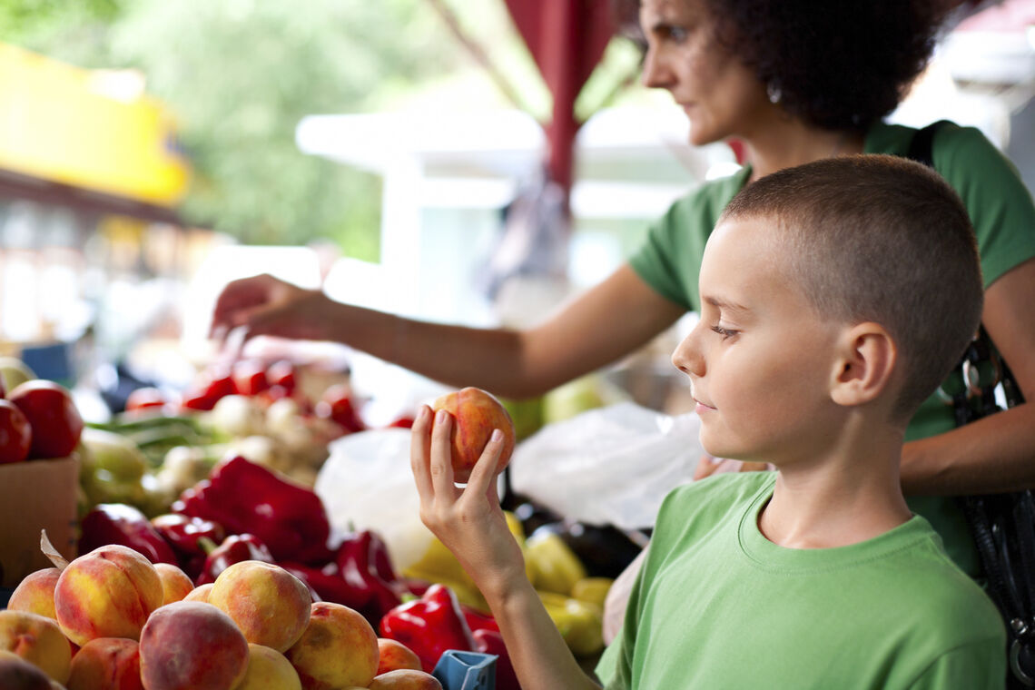 young boy examining apple at farmers market