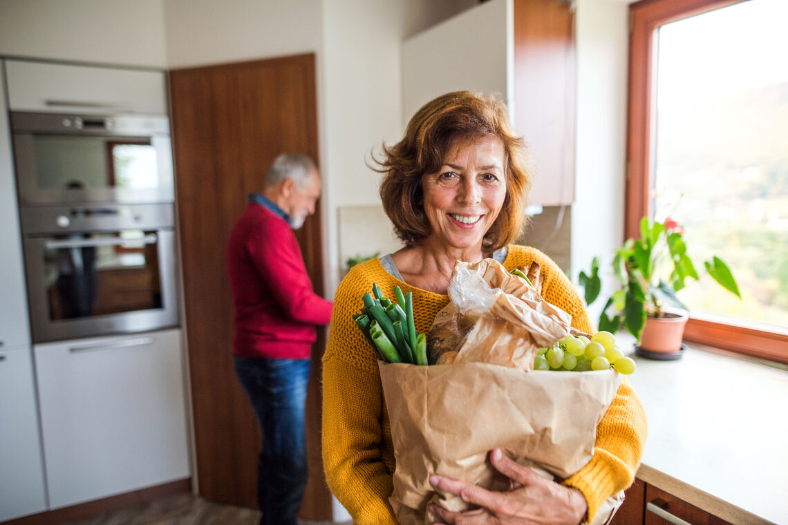 Senior couple unpacking groceries in the kitchen